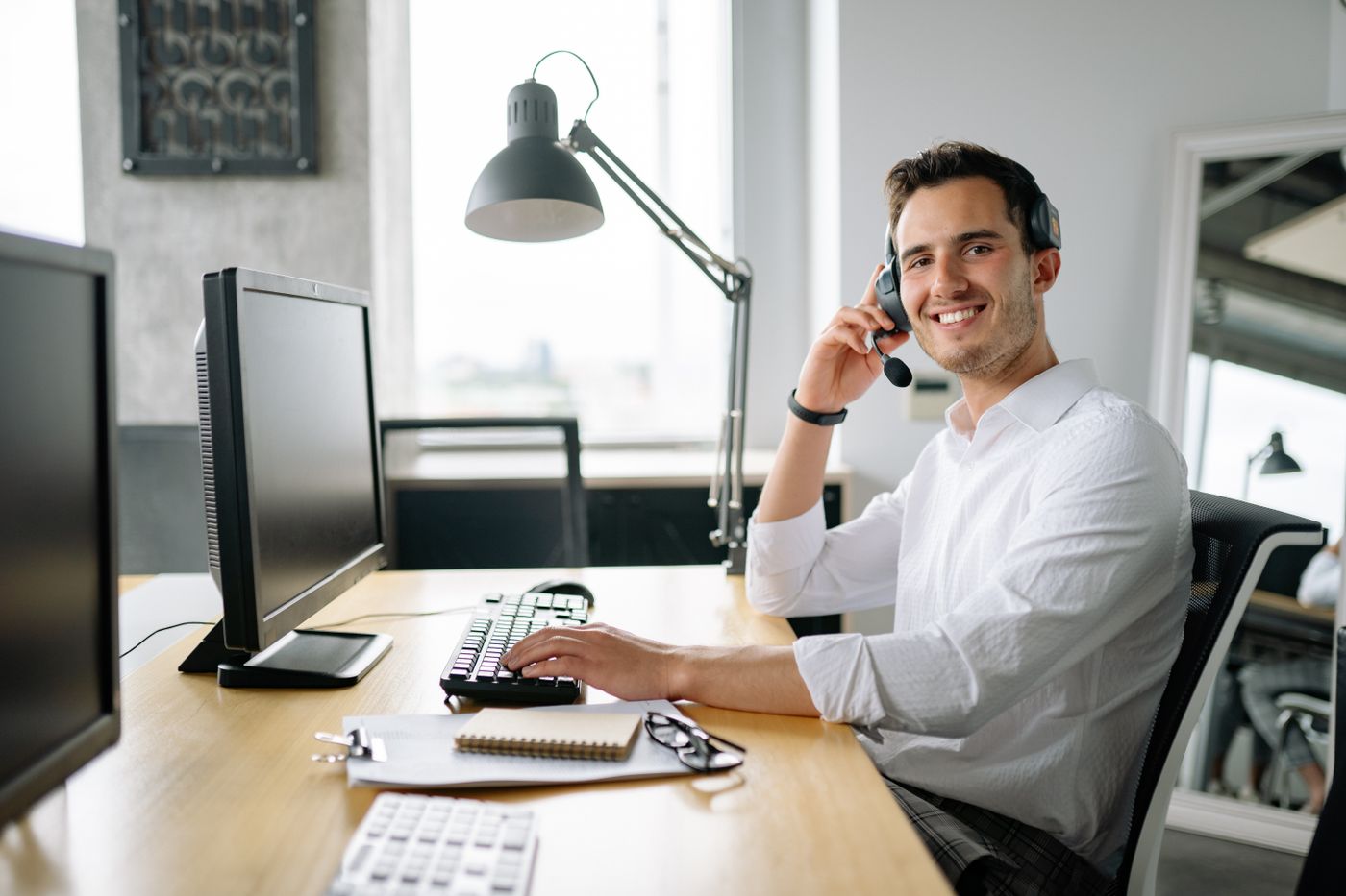 An AltaGrade team member at their desk, mid-conversation on the phone